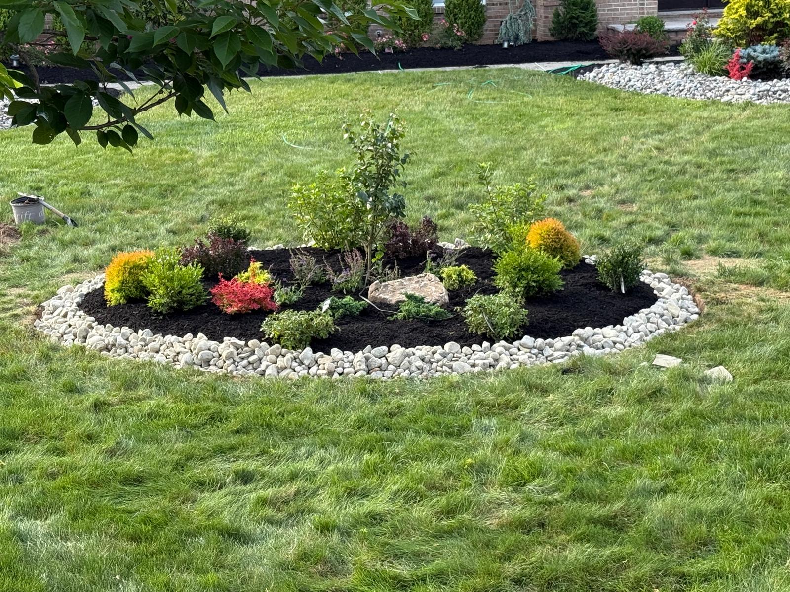 Colorful round planting bed with river rock border